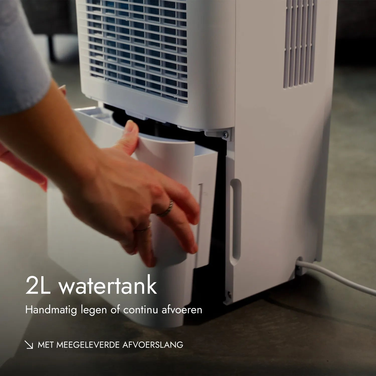 Eine Person zieht den 2L Wassertank eines weißen Luftentfeuchters heraus.