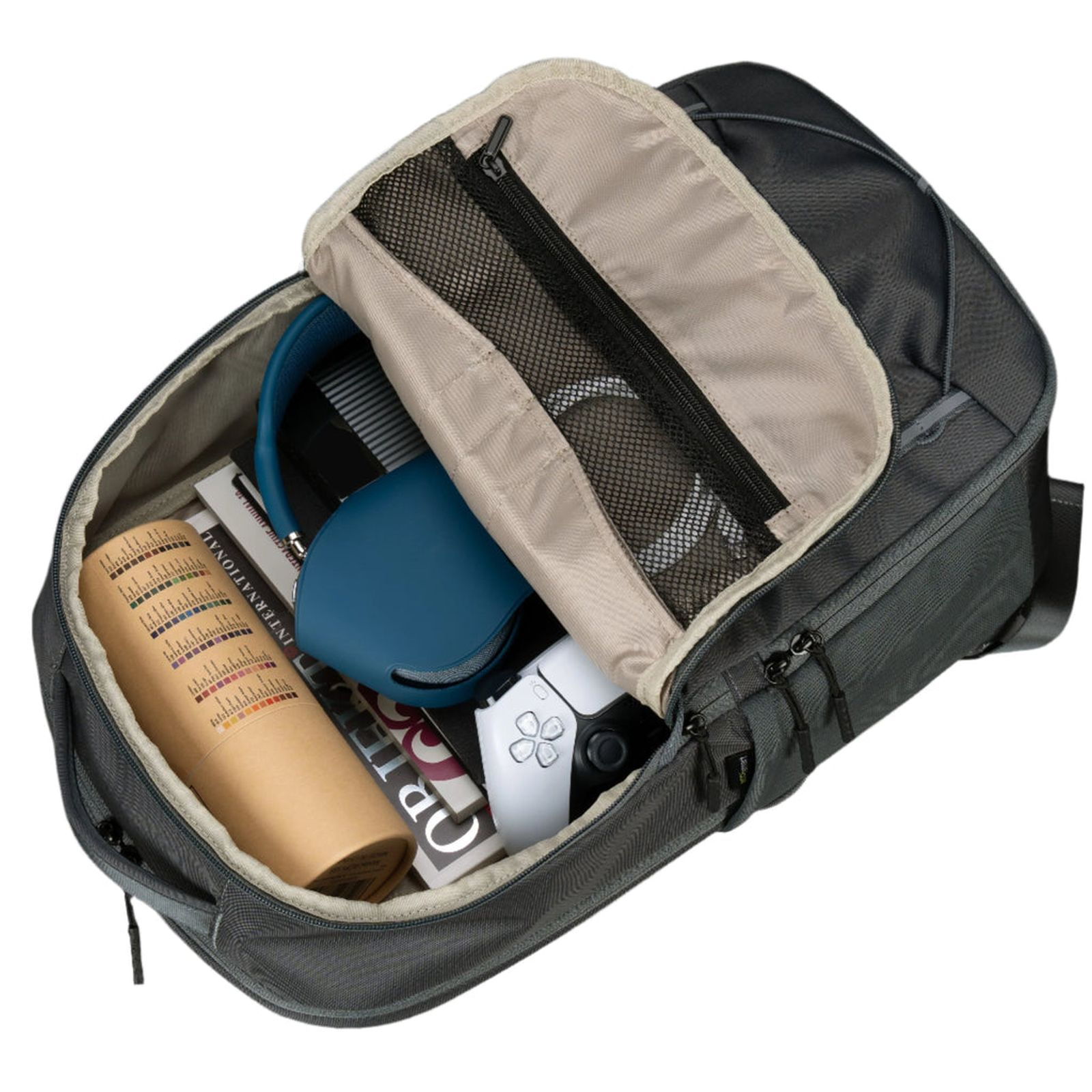 Una mochila gris abierta que contiene un tubo de cartón cilíndrico, libros, auriculares azules y un mando.