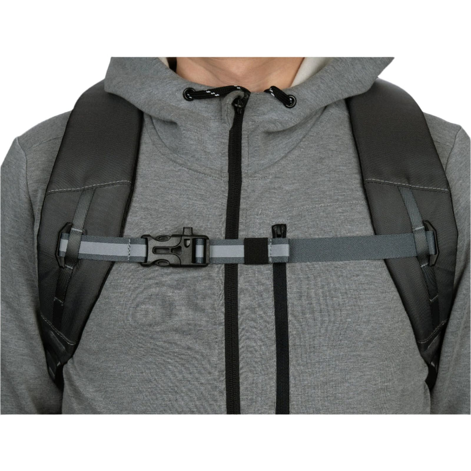 Persona con sudadera gris lleva una mochila con correa pectoral reflectante.