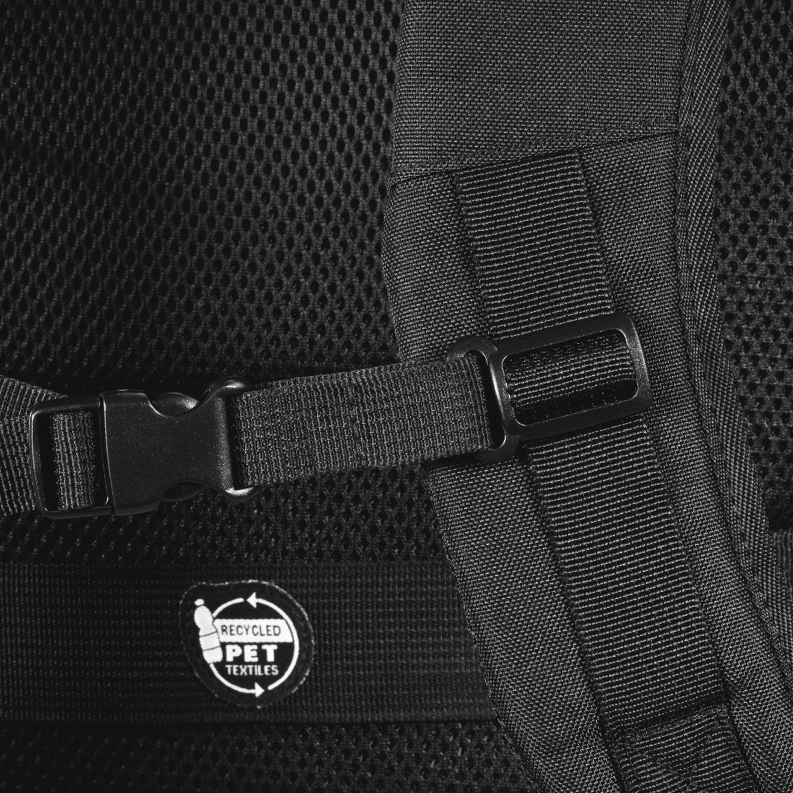 Nahaufnahme eines schwarzen Rucksackgurts mit Plastikschneppe und recyceltem PET-Textiletikett auf Mesh-Stoff.