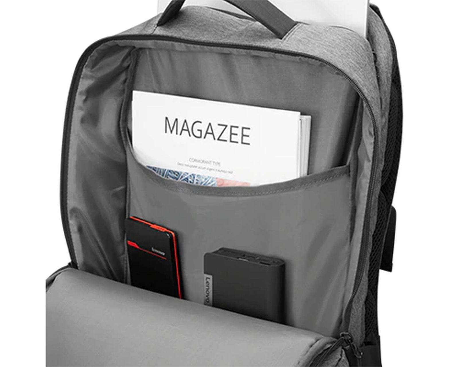 Una mochila gris abierta muestra una revista, un teléfono y una batería portátil en compartimentos.