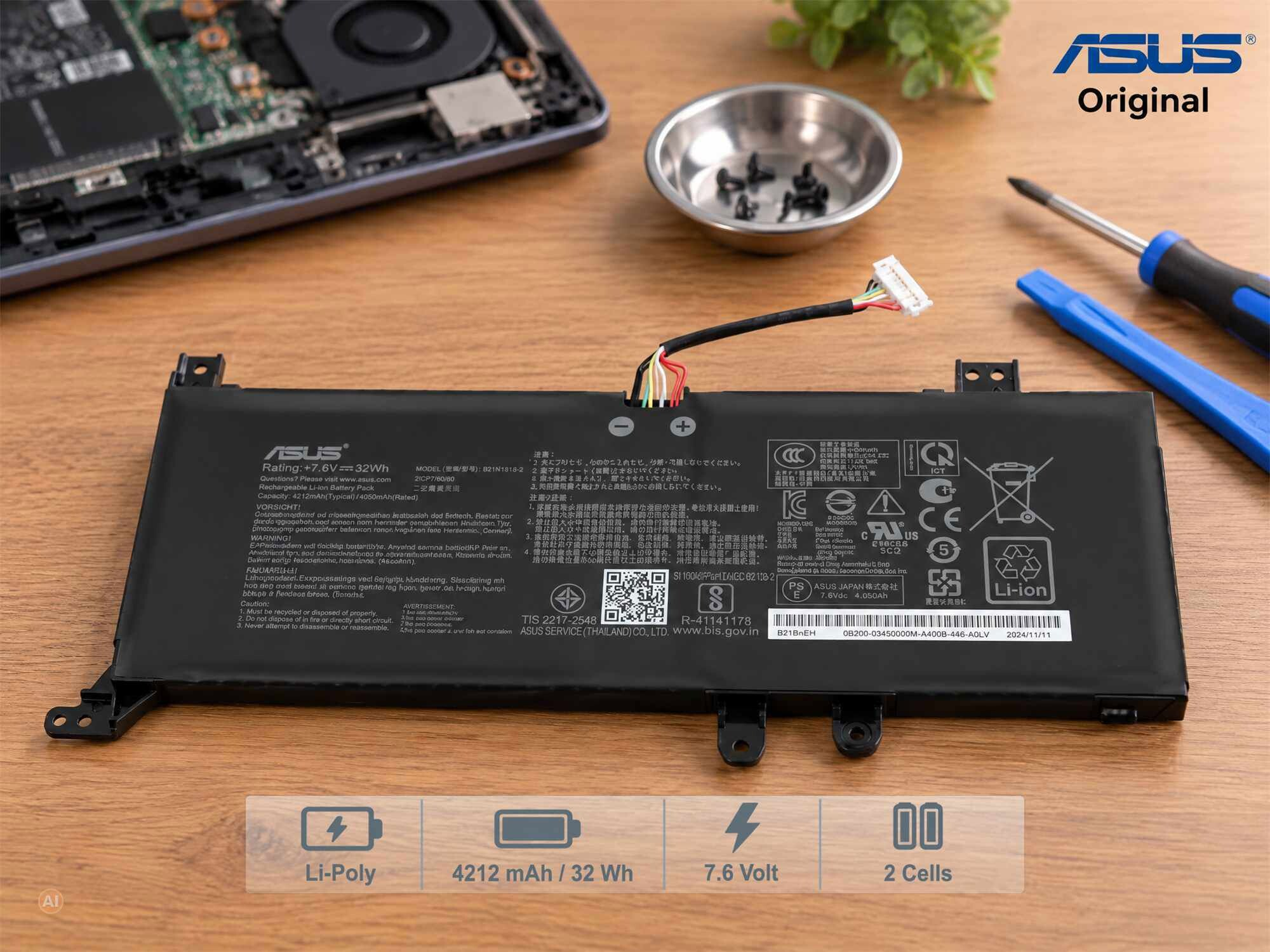 Ein ASUS-Laptop-Akku im Vordergrund mit Werkzeugen und Laptop im Hintergrund.