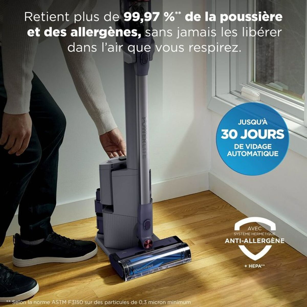 Persona che usa un aspirapolvere grigio su pavimento in legno con testo promozionale in francese.