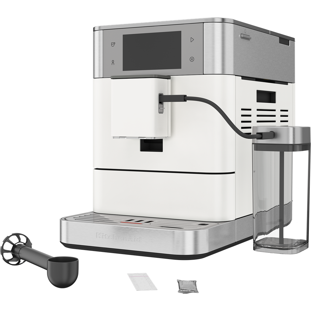 Une cafetière KitchenAid blanche et en inox avec réservoir de lait, cuillère et accessoires sur fond blanc.