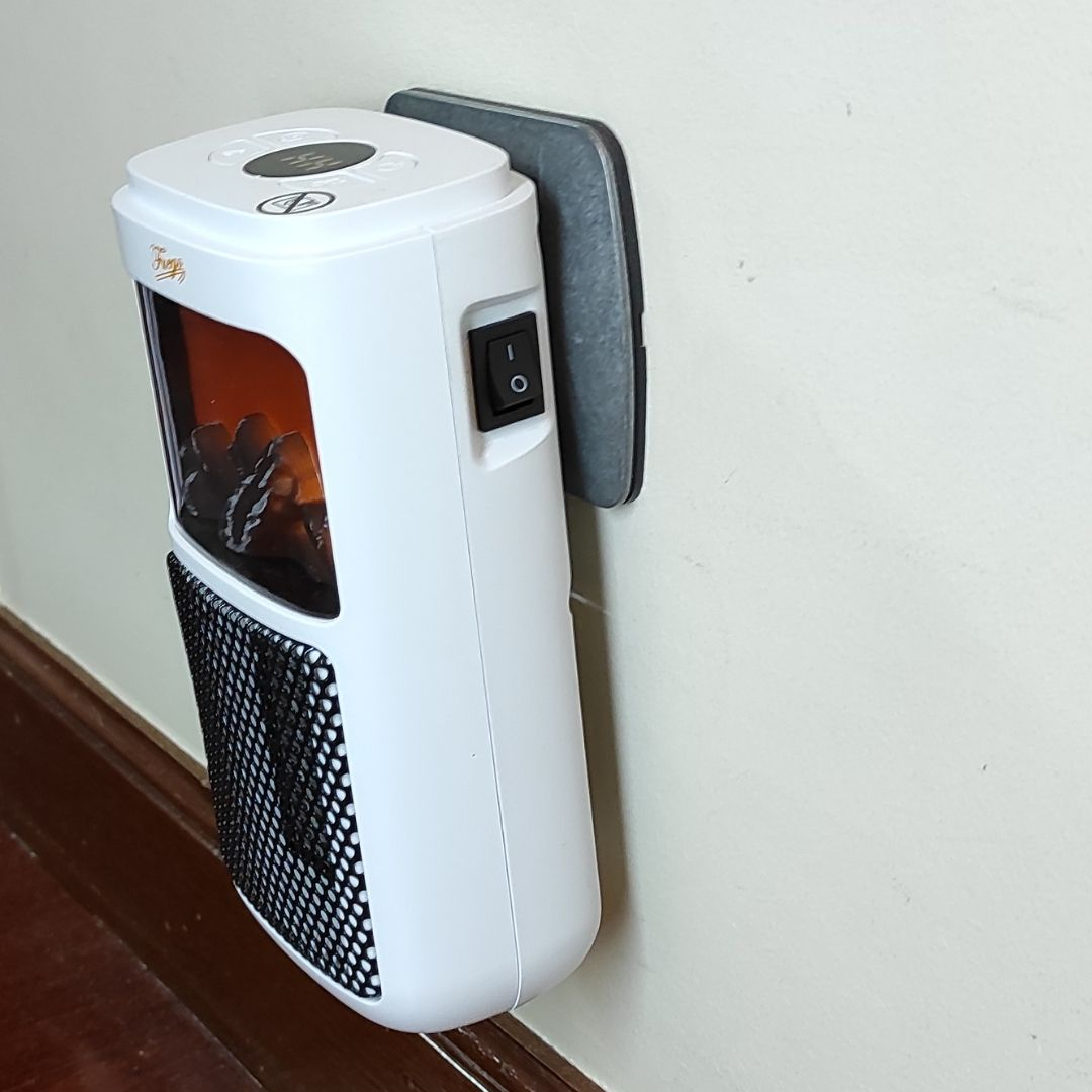 Un minicalefactor blanco con pantalla digital y efecto de chimenea está enchufado a la pared.