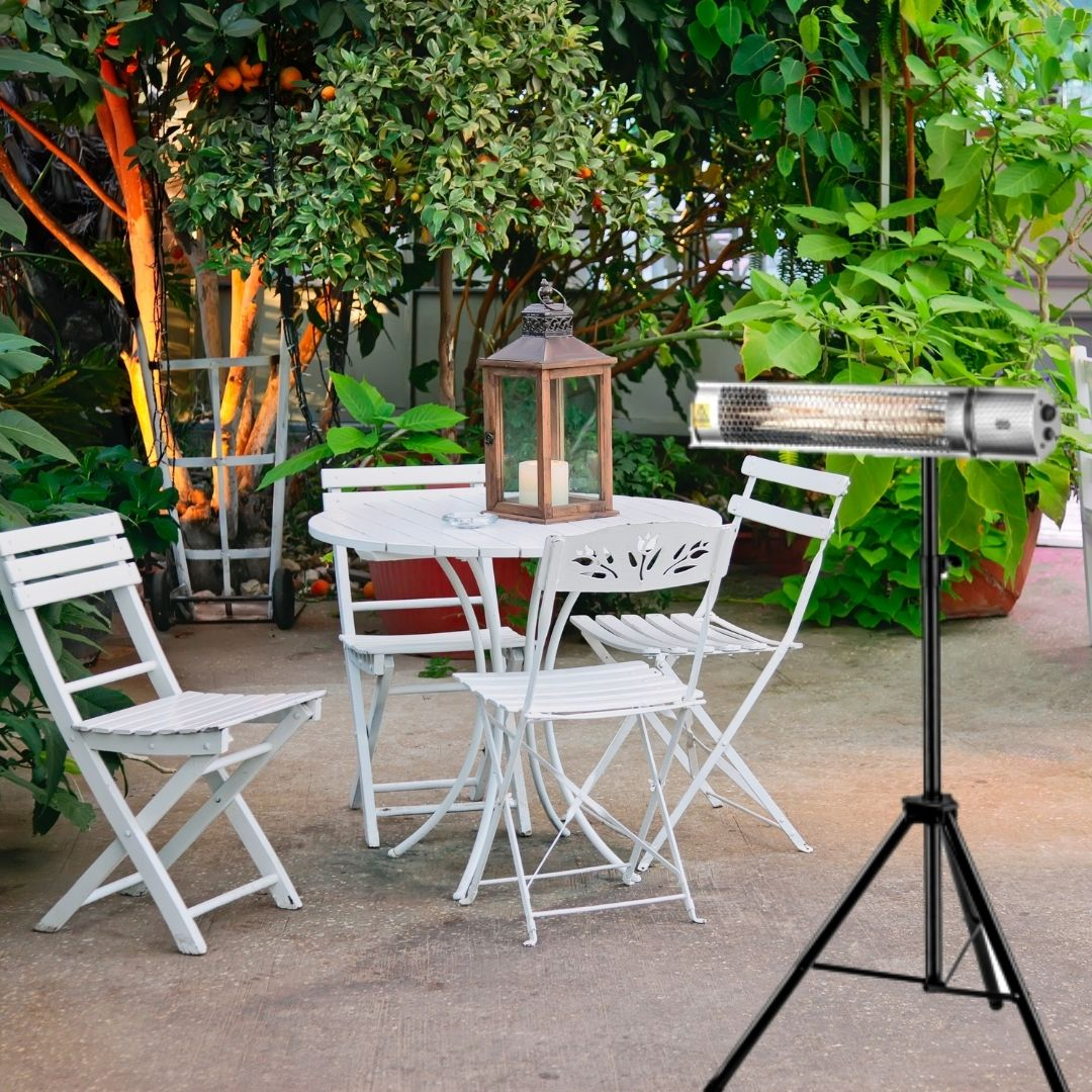 Un calefactor de patio se encuentra en un trípode con sillas blancas, una mesa, un farol y plantas verdes.