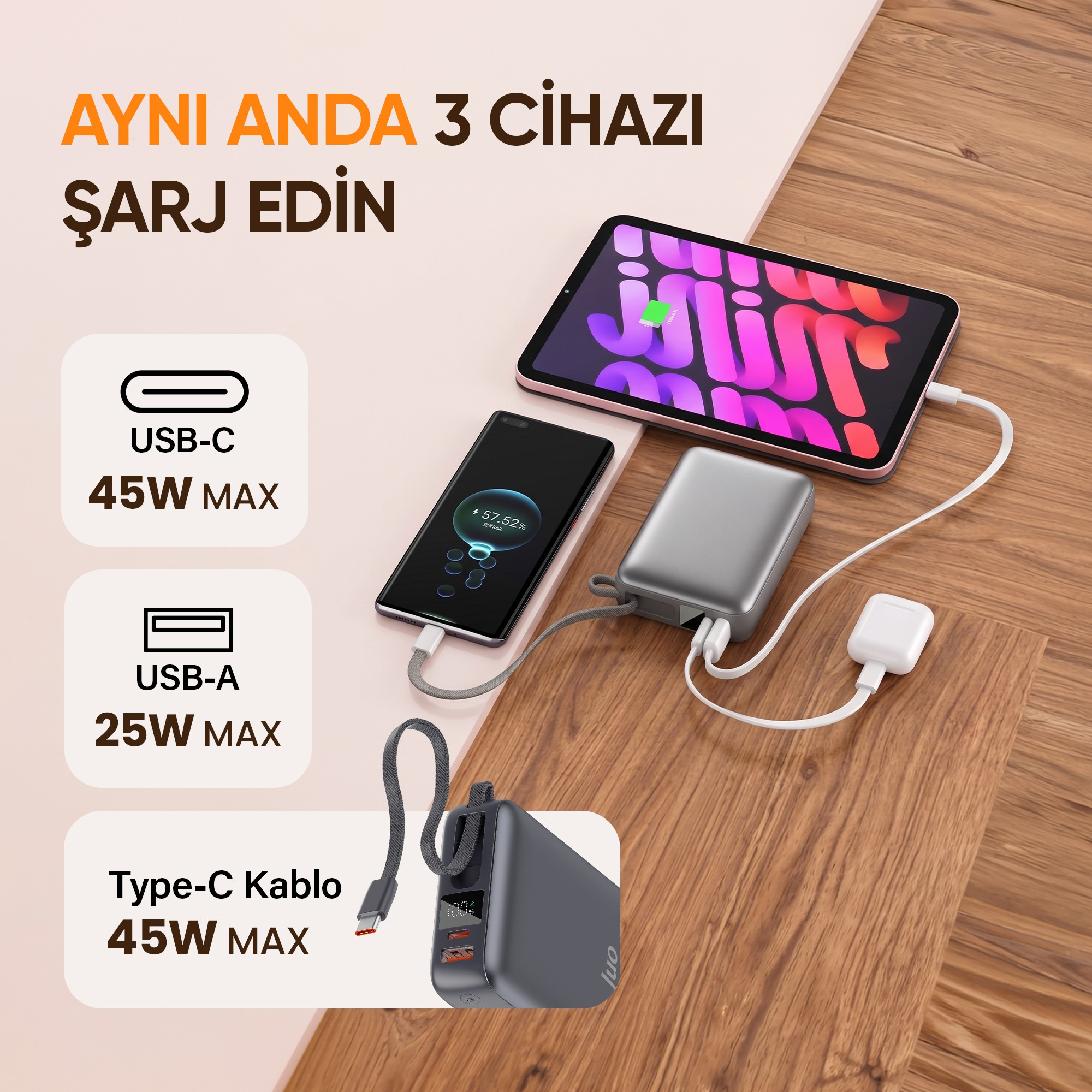 Gri renkli bir powerbank, ahşap yüzeyde aynı anda akıllı telefon, tablet ve kabloyu şarj ediyor.