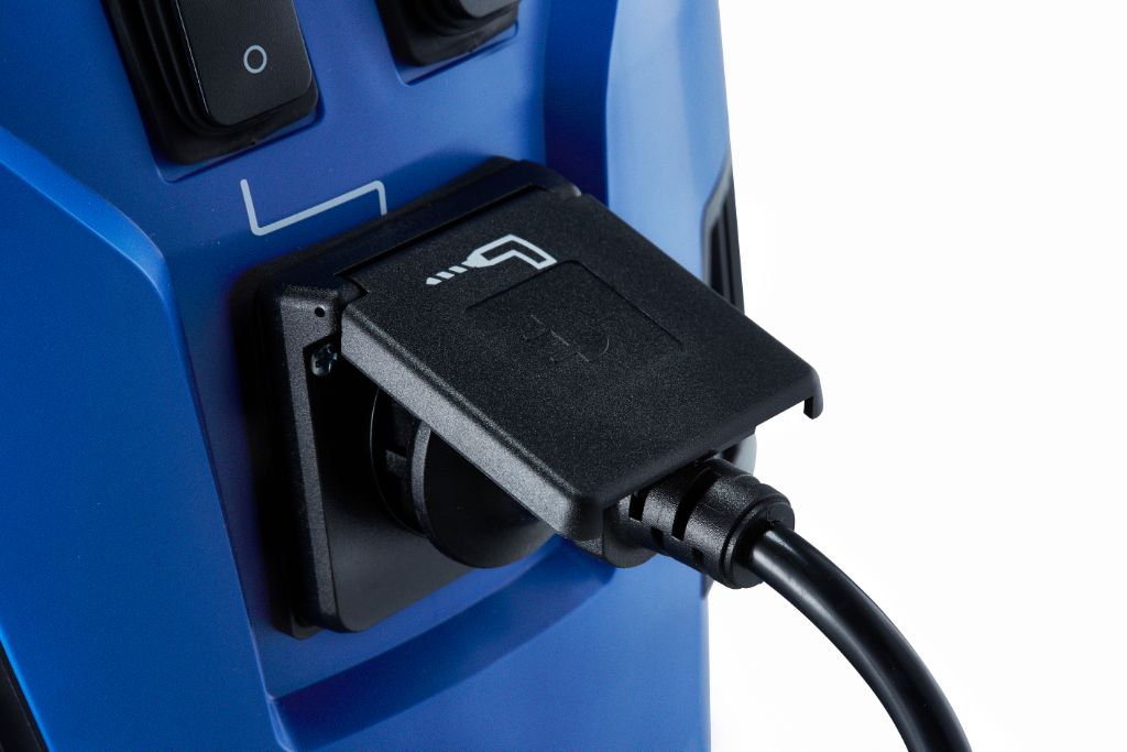 Un cordon d'alimentation noir est branché sur une prise avec un couvercle de protection sur un appareil bleu.
