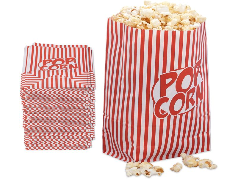 Rot-weiß gestreifte Popcorntüte voll Popcorn mit einem Stapel flacher Tüten daneben auf weißem Grund.