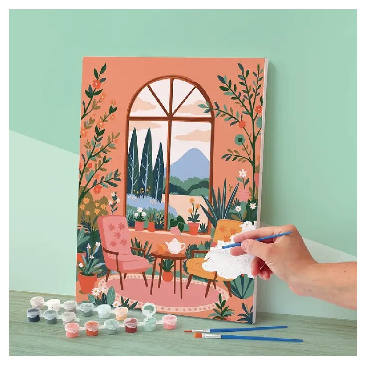 Eine Hand bemalt eine bunte Leinwand mit Stühlen, Pflanzen und Fensterblick.