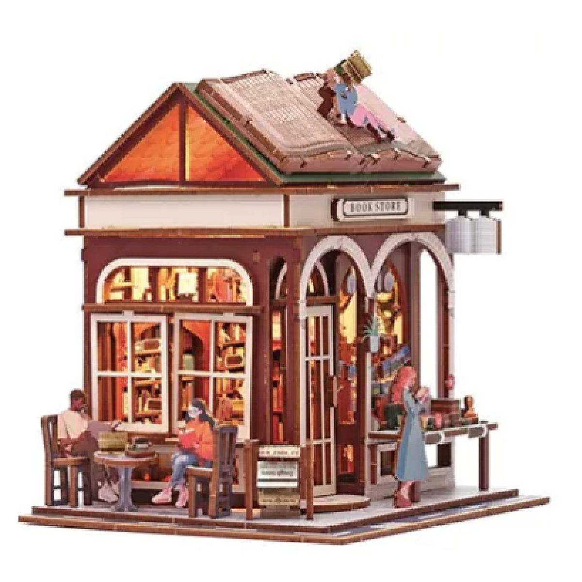 Miniatur-Holzbuchhandlung mit beleuchtetem Innenraum, Figuren beim Lesen und einem großen Buch als Dach.