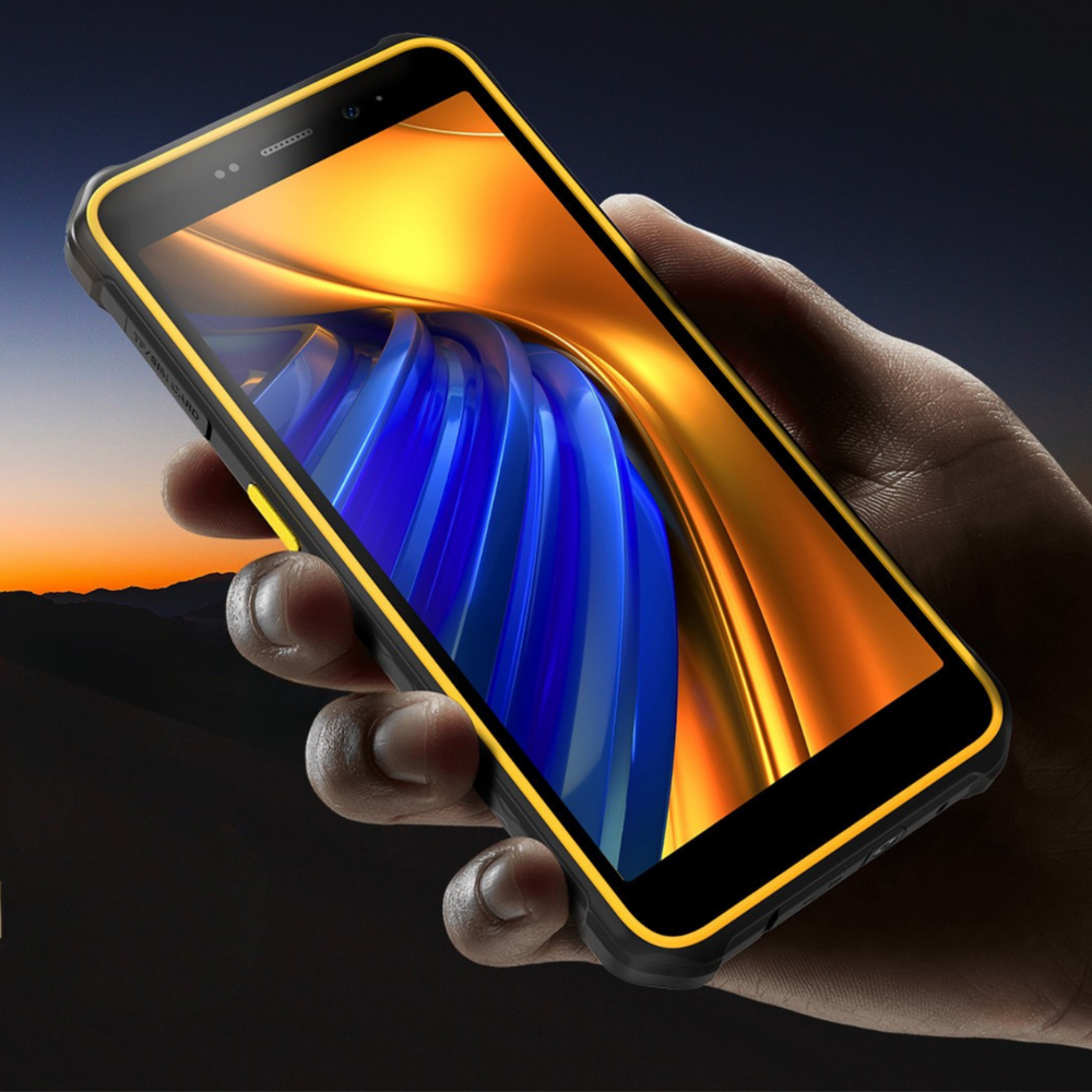 Eine Hand hält ein robustes Smartphone mit gelbem Rahmen und blau-orangefarbenem Display, im Hintergrund ist eine Abenddämmerung.