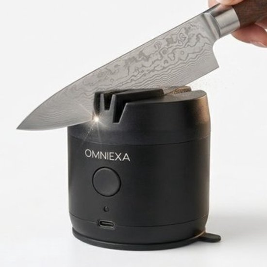 A hand-held knife is being sharpened on a black electric knife sharpener.