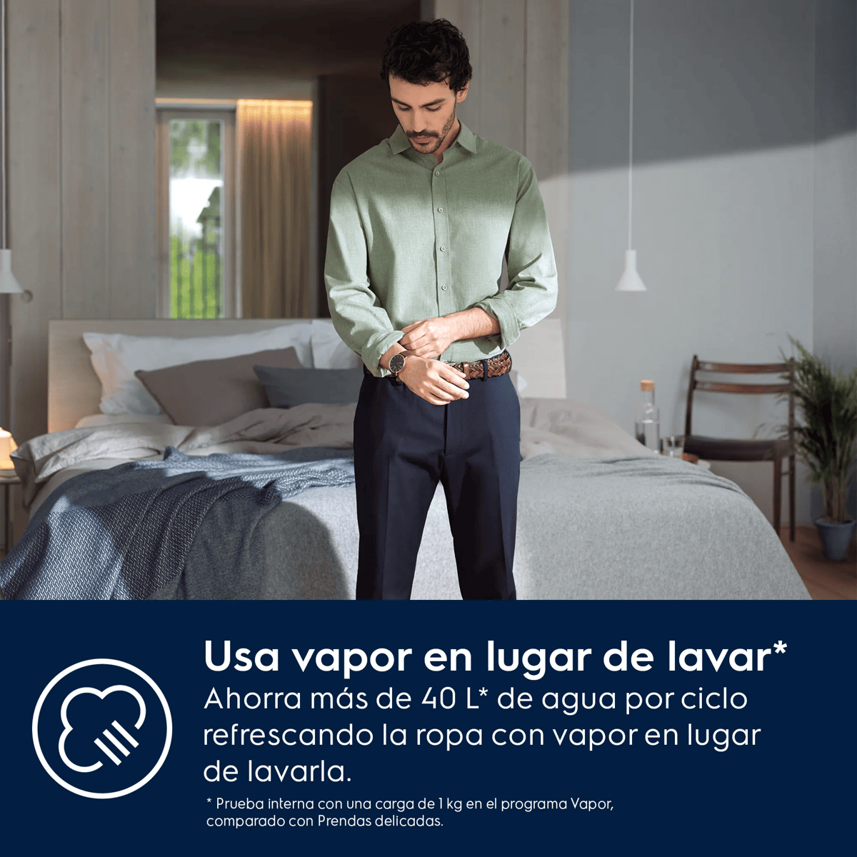 Un hombre con camisa verde clara y pantalón oscuro está en un dormitorio frente a una cama hecha.