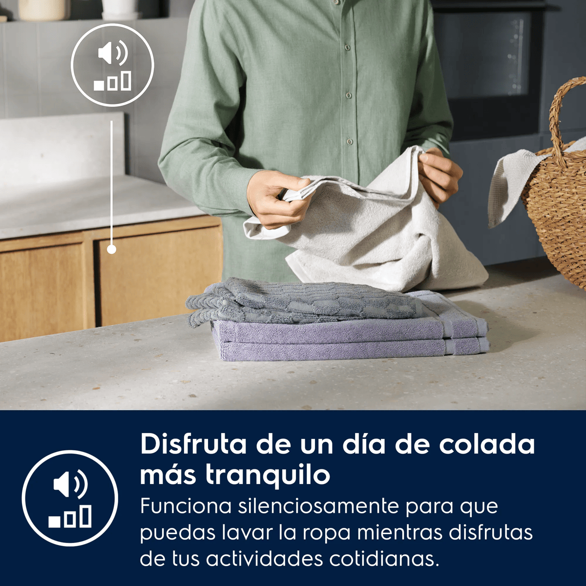 Una persona con camisa verde dobla ropa blanca en una cocina, con toallas dobladas en el mostrador.