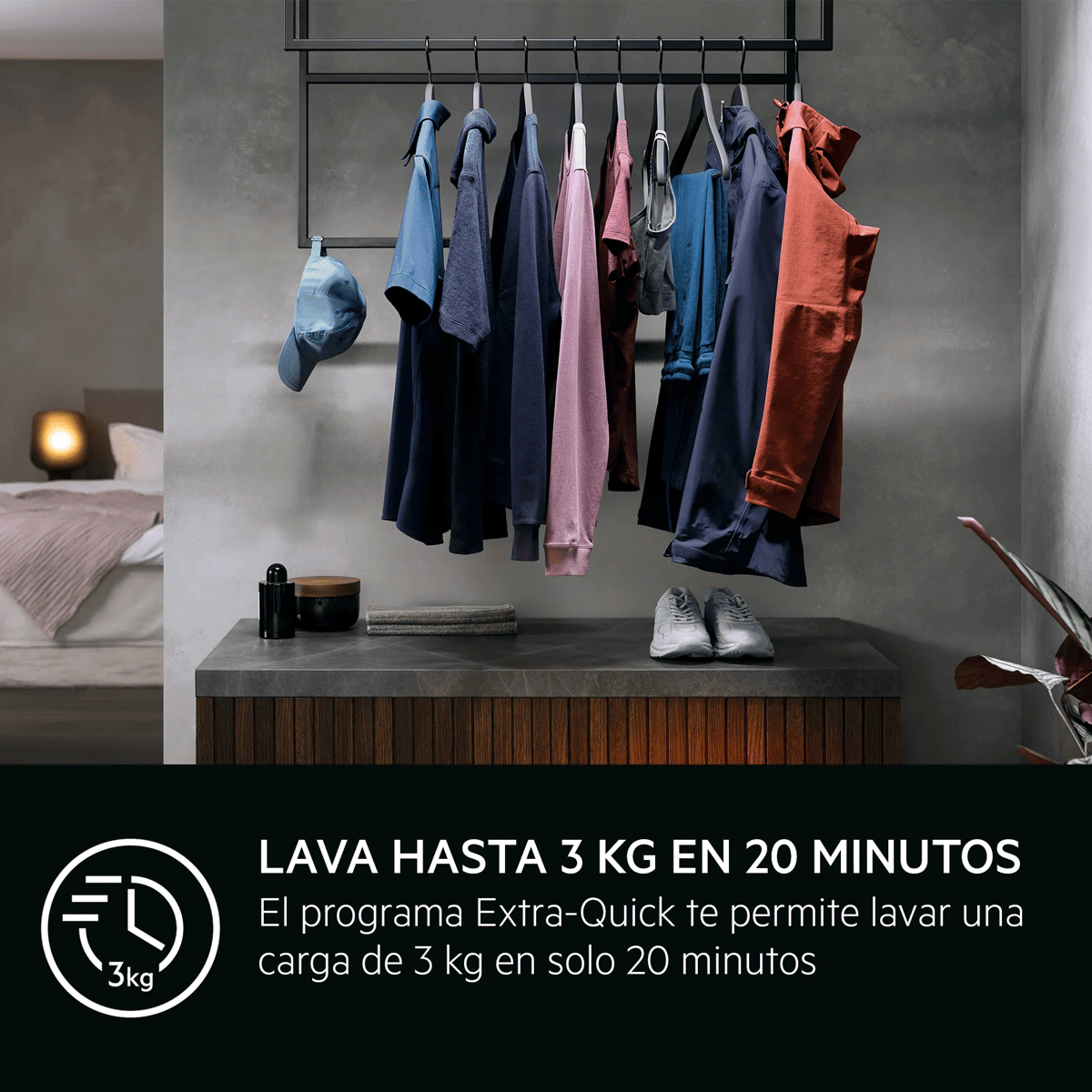 Ropa colgada en una barra negra sobre una mesa de madera, con un dormitorio al fondo.