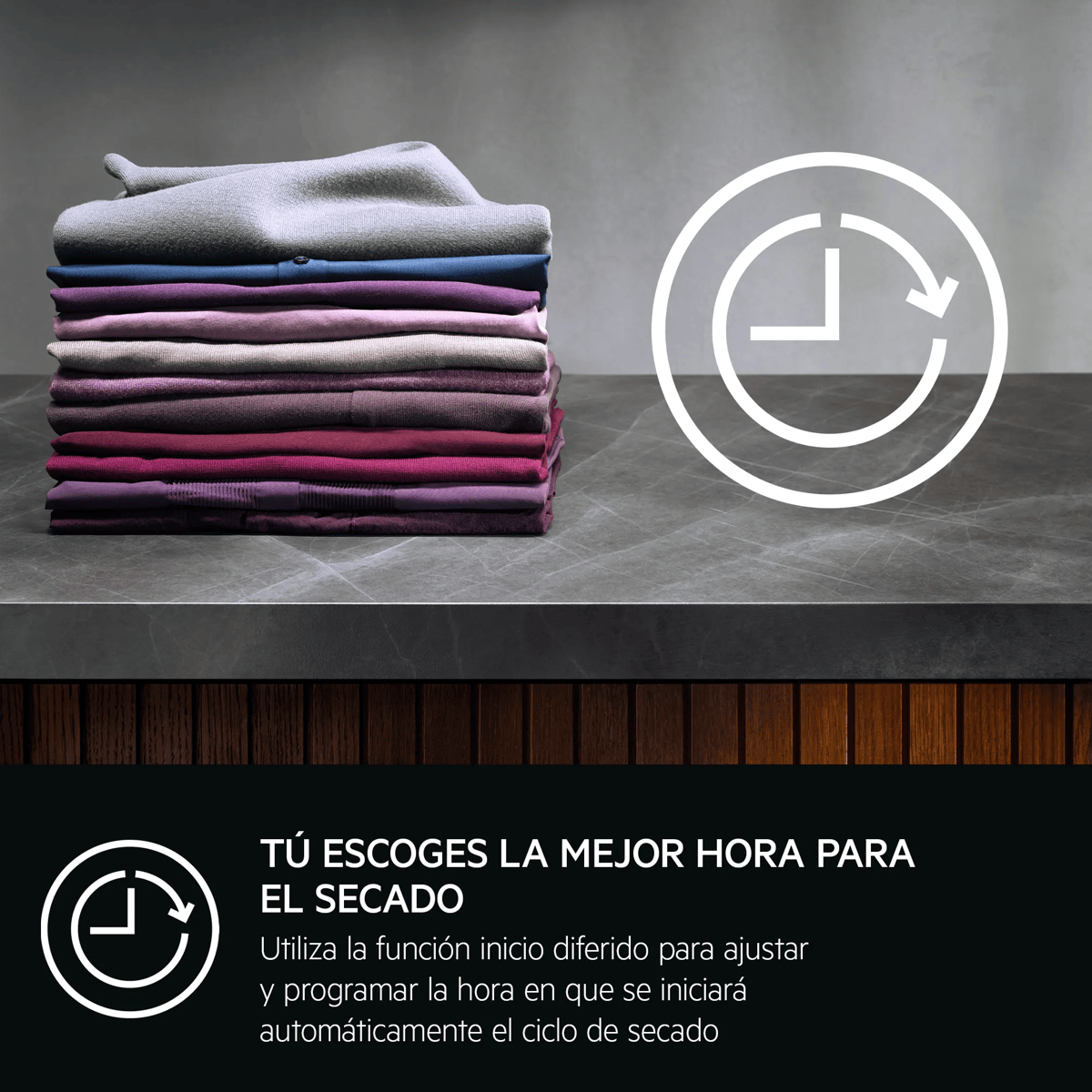 Una pila ordenada de ropa colorida doblada sobre una superficie de mármol con un icono de reloj.