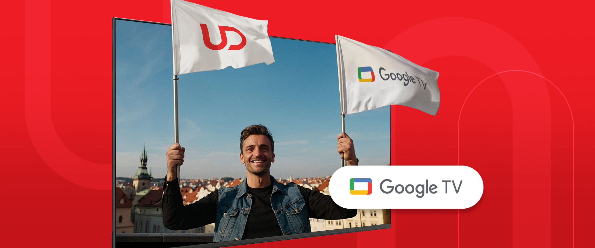 Uśmiechnięty mężczyzna trzyma dwie flagi z logo UD i Google TV na tle miasta.