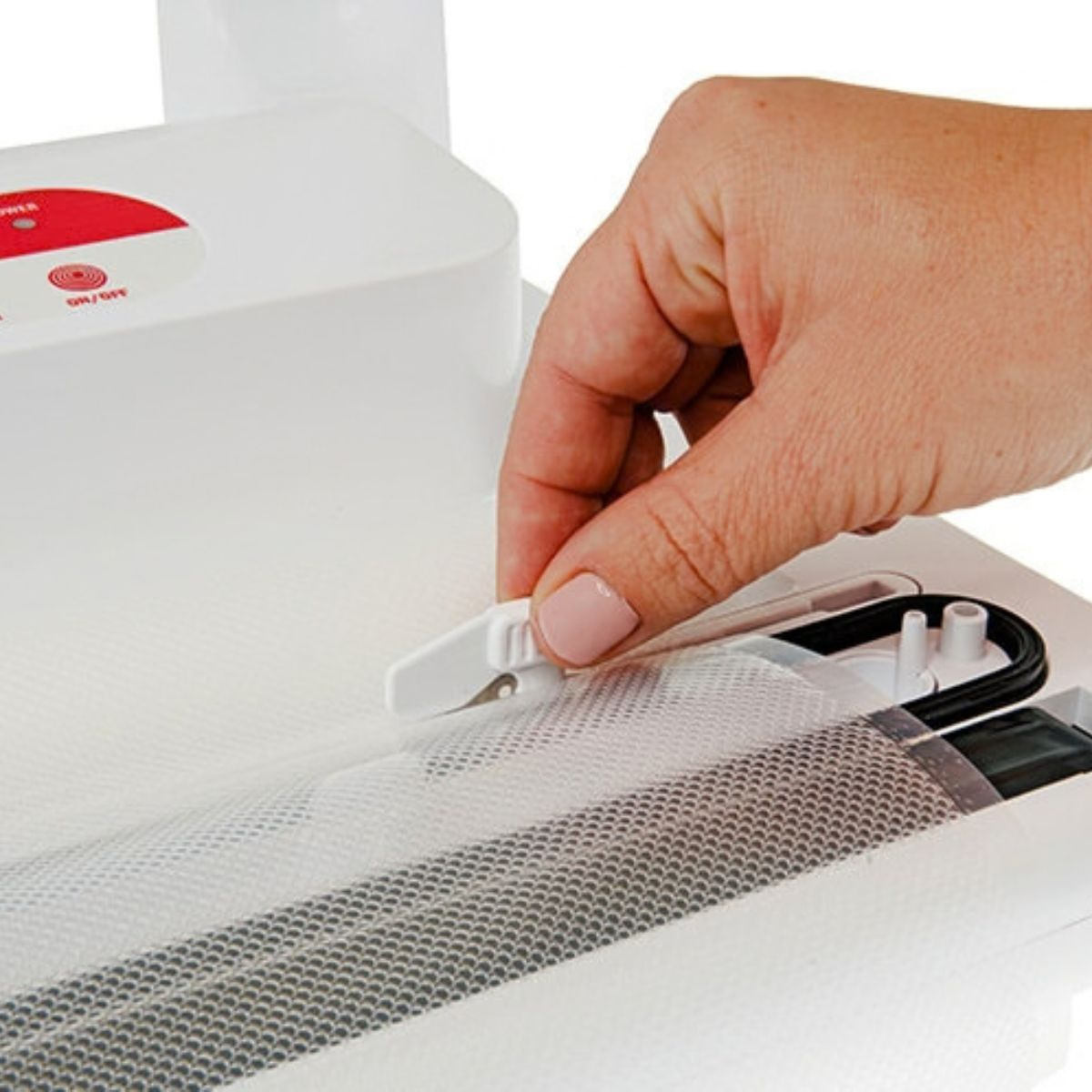 Dłoń prowadzi małe białe ostrze po teksturowanej plastikowej torbie.