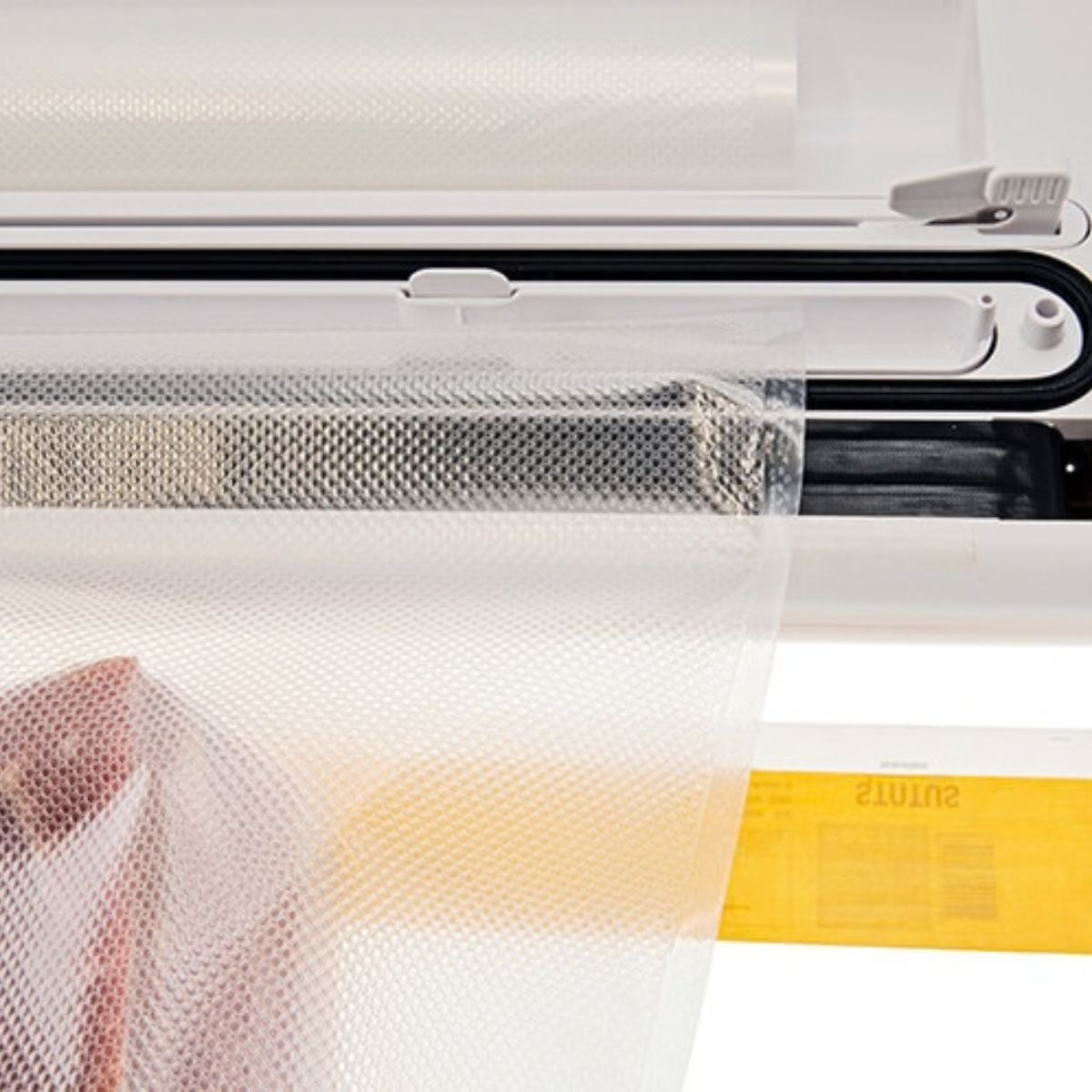 Zgrzewarka próżniowa z fakturowaną plastikową torbom i mięsem.