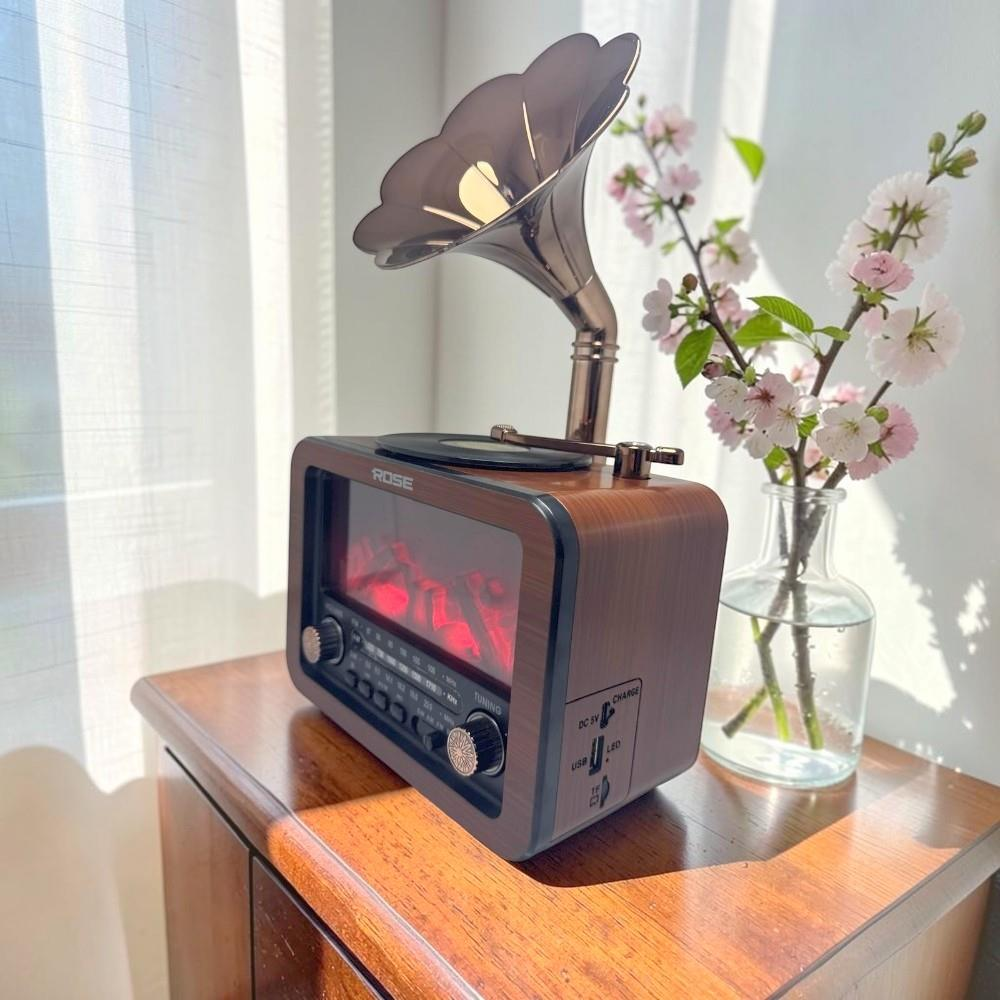Gramofon hunili ahşap retro radyo ve ahşap masada pembe çiçekli bir vazo.