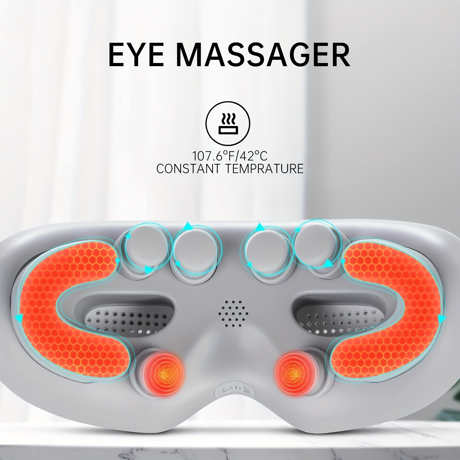 Weißes Augenmassagegerät mit beheizten orangefarbenen Wabenmustern und Massageköpfen, Text 'EYE MASSAGER'.