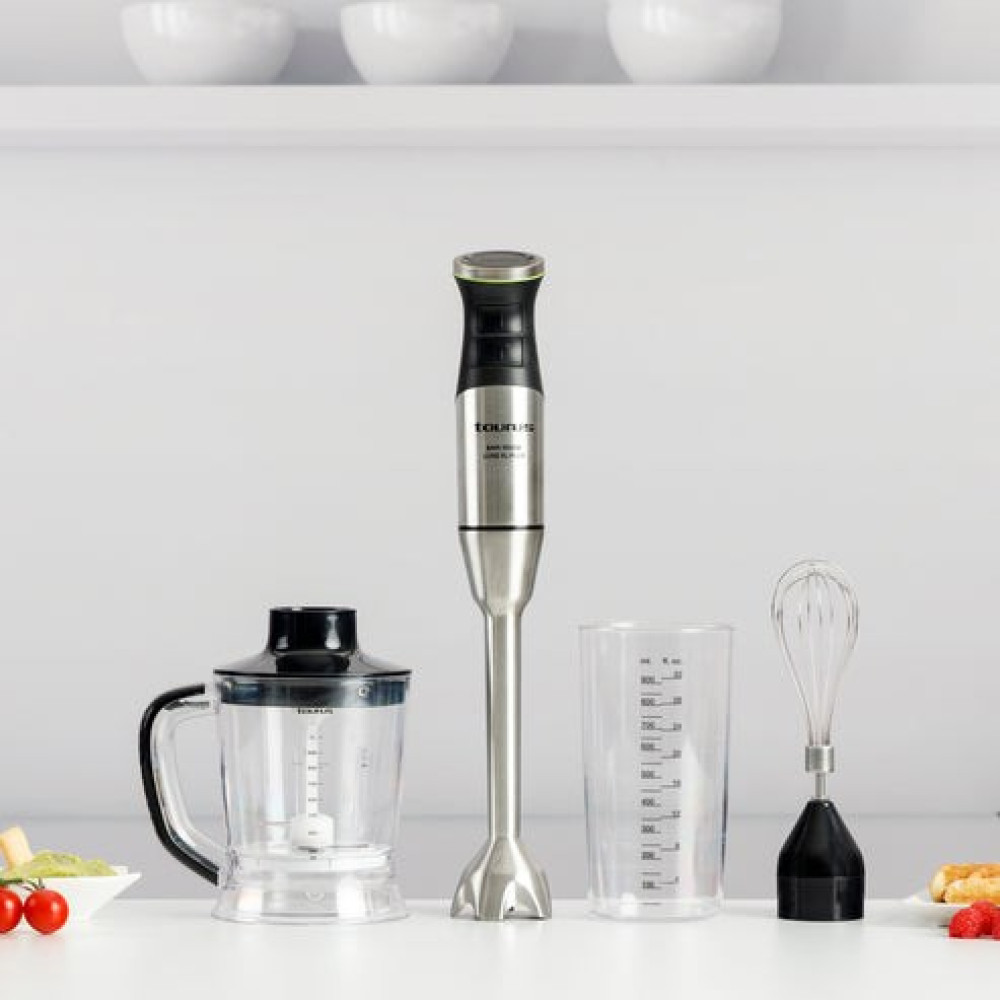 Un set di frullatore a immersione in acciaio inossidabile con tritatutto, bicchiere e frusta su un piano da cucina.
