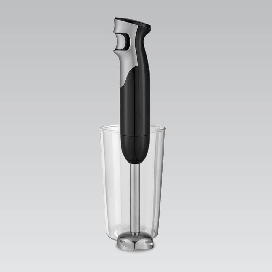 Czarno-srebrny blender ręczny stoi w przezroczystym kielichu na szarym tle.