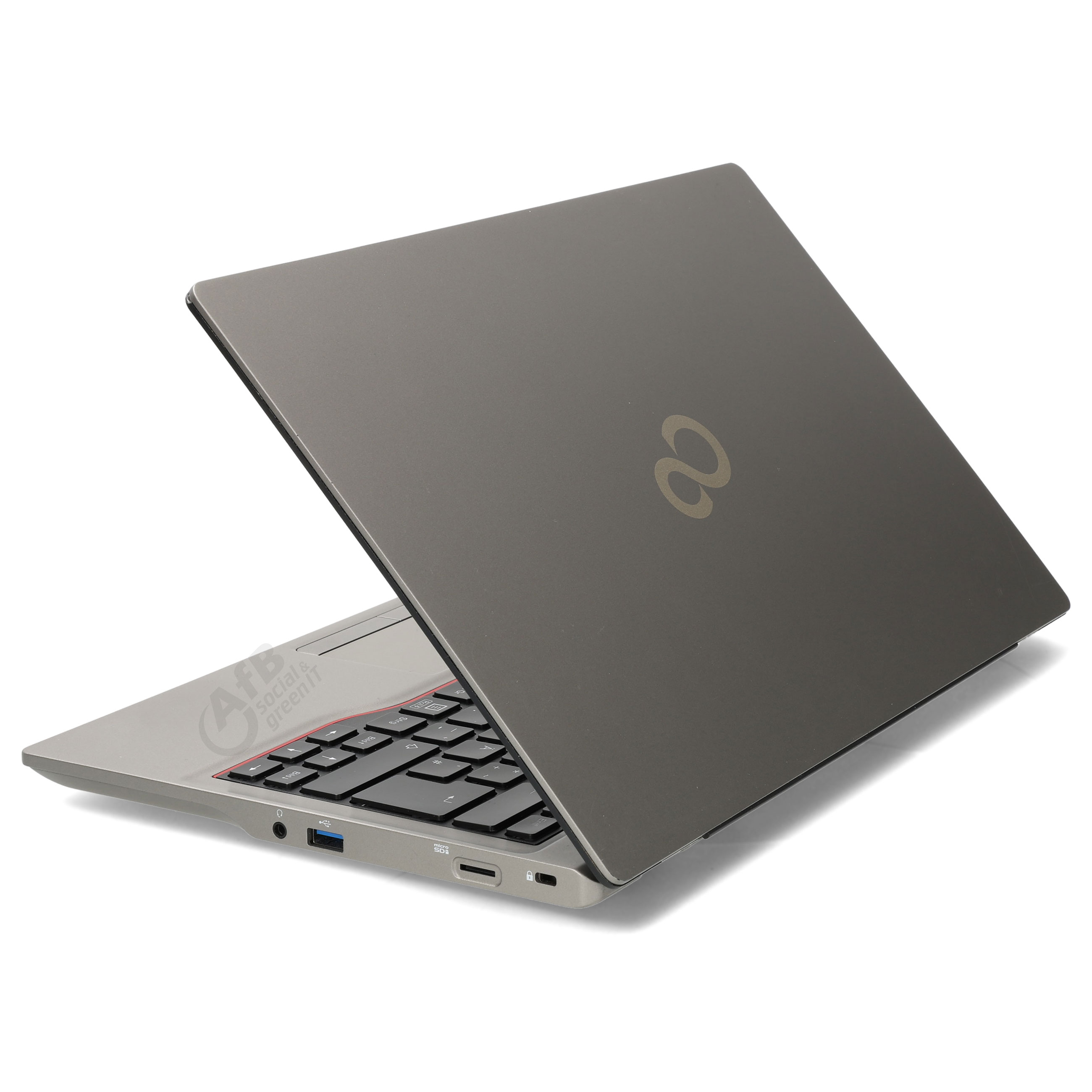 Ein grauer Laptop mit geöffnetem Bildschirm steht auf einer weißen Oberfläche. Man sieht die Tastatur und Anschlüsse.