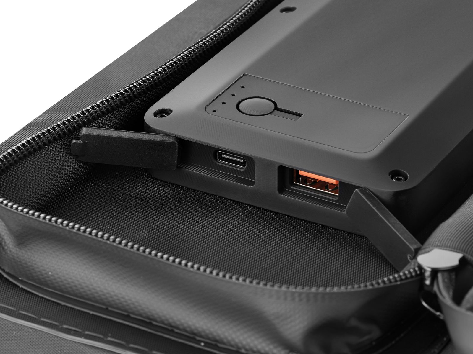 Eine schwarze Powerbank mit offenen USB-Anschlüssen liegt in einem Koffer.