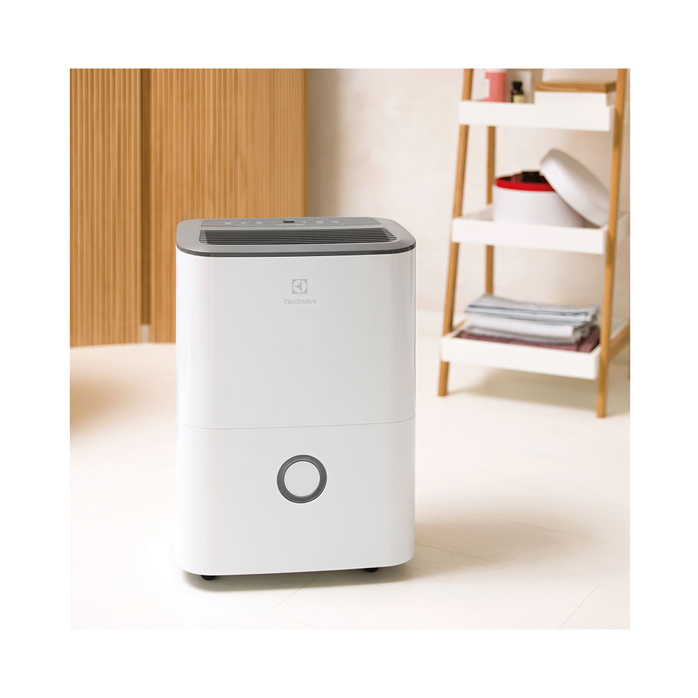 Un déshumidificateur blanc Electrolux se trouve dans une pièce lumineuse devant une étagère en bois.