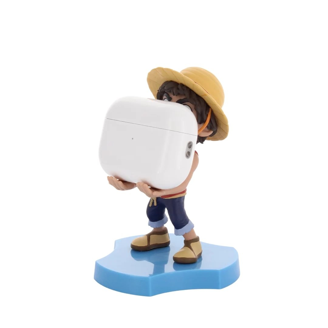 Una figura de anime con sombrero de paja y pantalones cortos azules lleva un estuche blanco grande de auriculares.