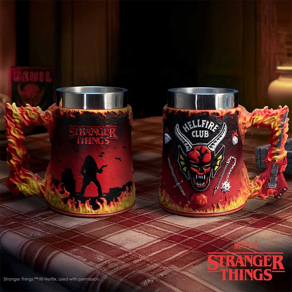 Dos tazas de Hellfire de Stranger Things con llamas y motivos diabólicos en una mesa a cuadros rojos.
