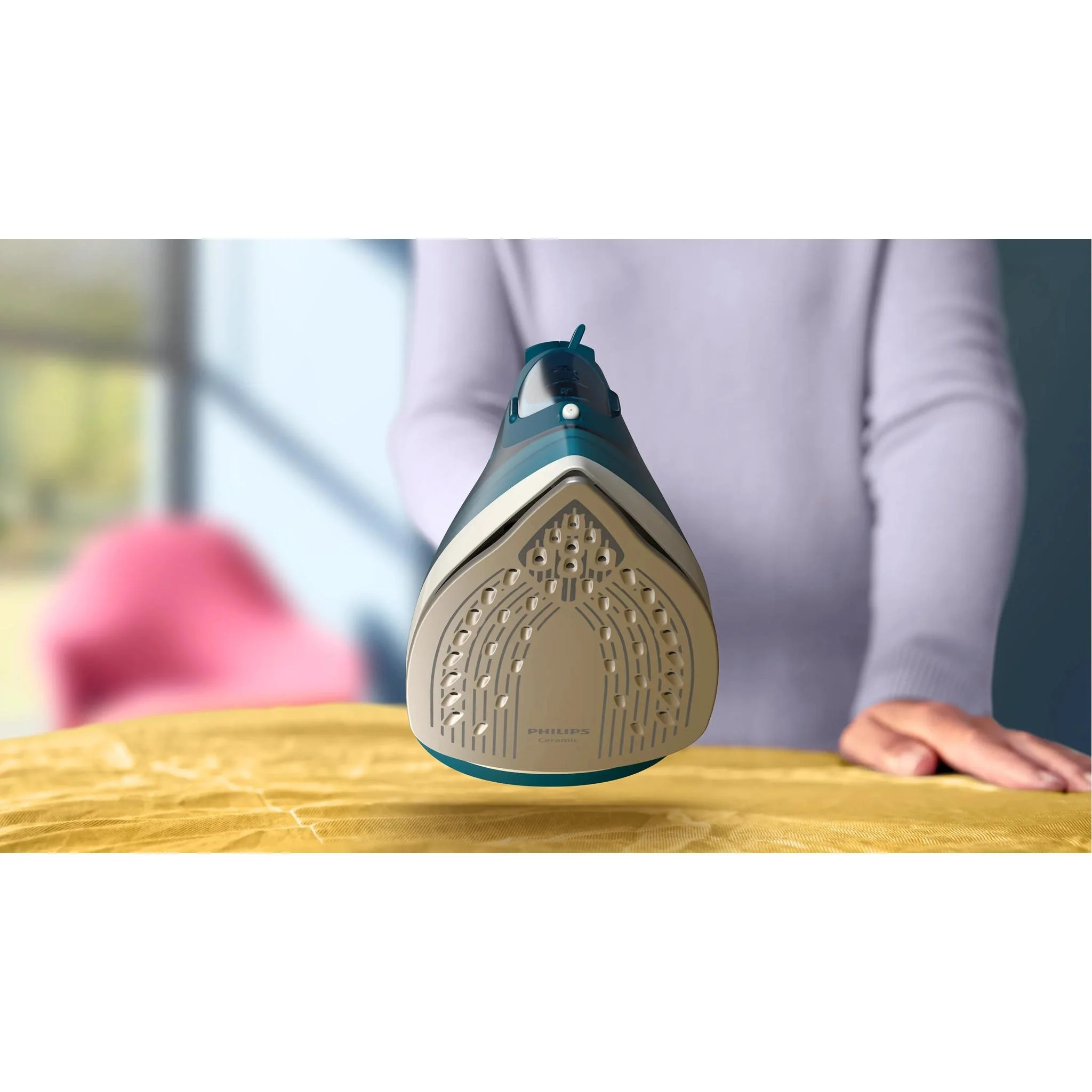 Eine Person hält ein blau-weißes Philips Keramikbügeleisen über ein gelbes Brett.