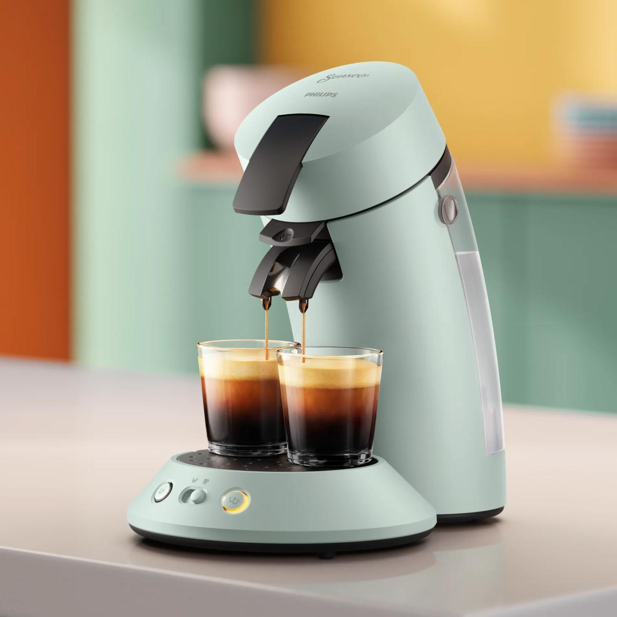 Una macchina da caffè Senseo verde menta eroga due tazze su un ripiano.