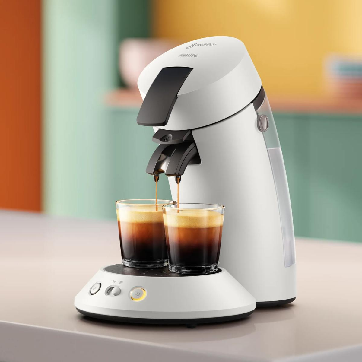 Una macchina da caffè Senseo bianca eroga caffè fresco in due bicchieri di vetro su un bancone.