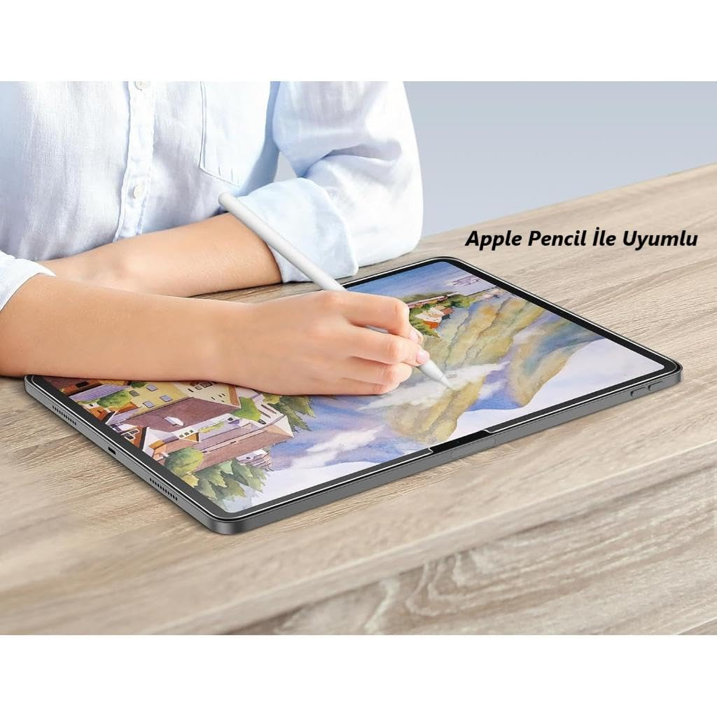 Bir kişi ahşap masa üzerinde Apple Pencil ile tablete çizim yapıyor.
