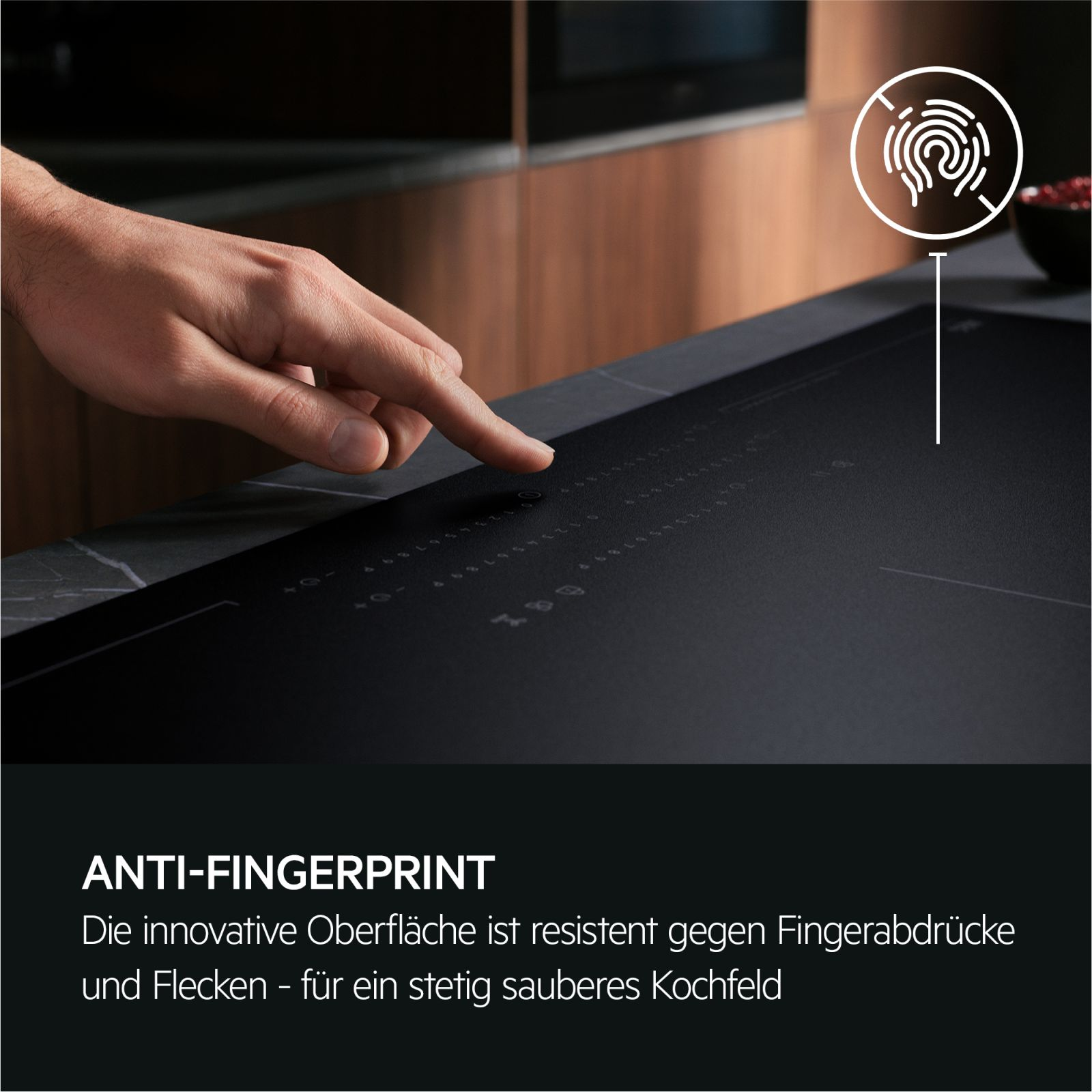 Una mano tocca un piano cottura nero anti-impronta con un'icona di impronta digitale.