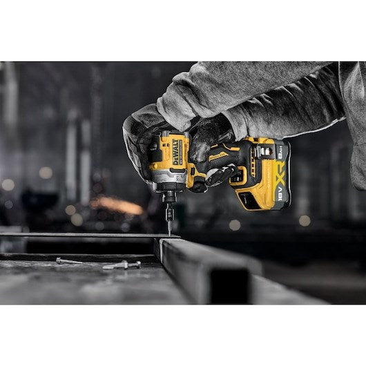 Un trabajador con guantes usa un atornillador de impacto inalámbrico DeWalt amarillo y negro.