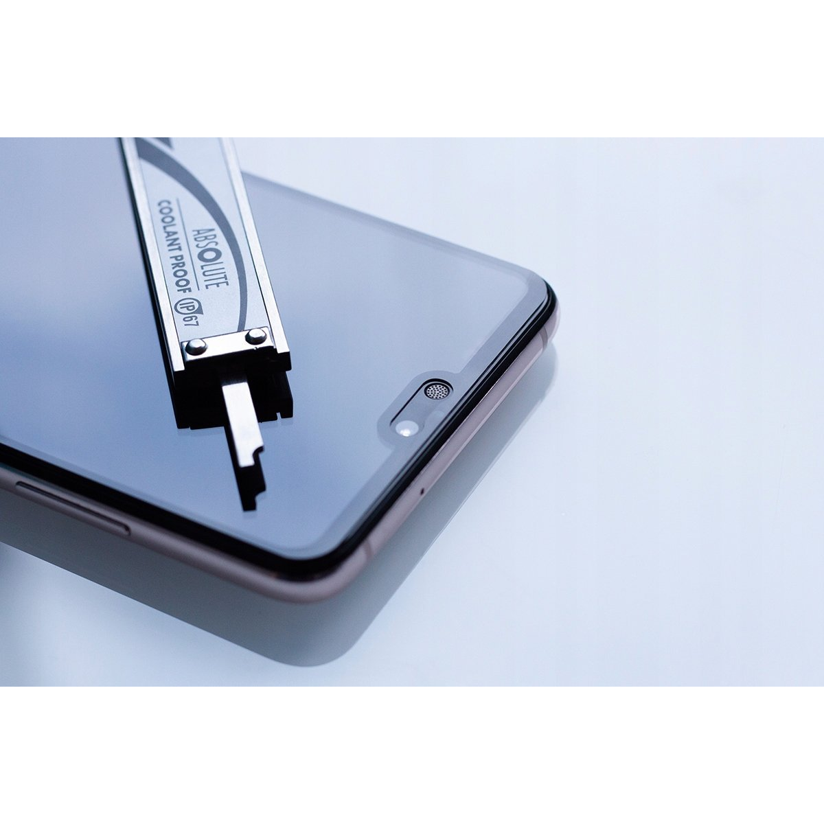 Una herramienta de calibre de metal descansa sobre la pantalla de un teléfono inteligente con fondo azul claro.