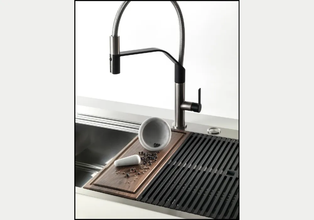 Moderno lavello da cucina in acciaio inox con rubinetto nero, asse in legno e mortaio.