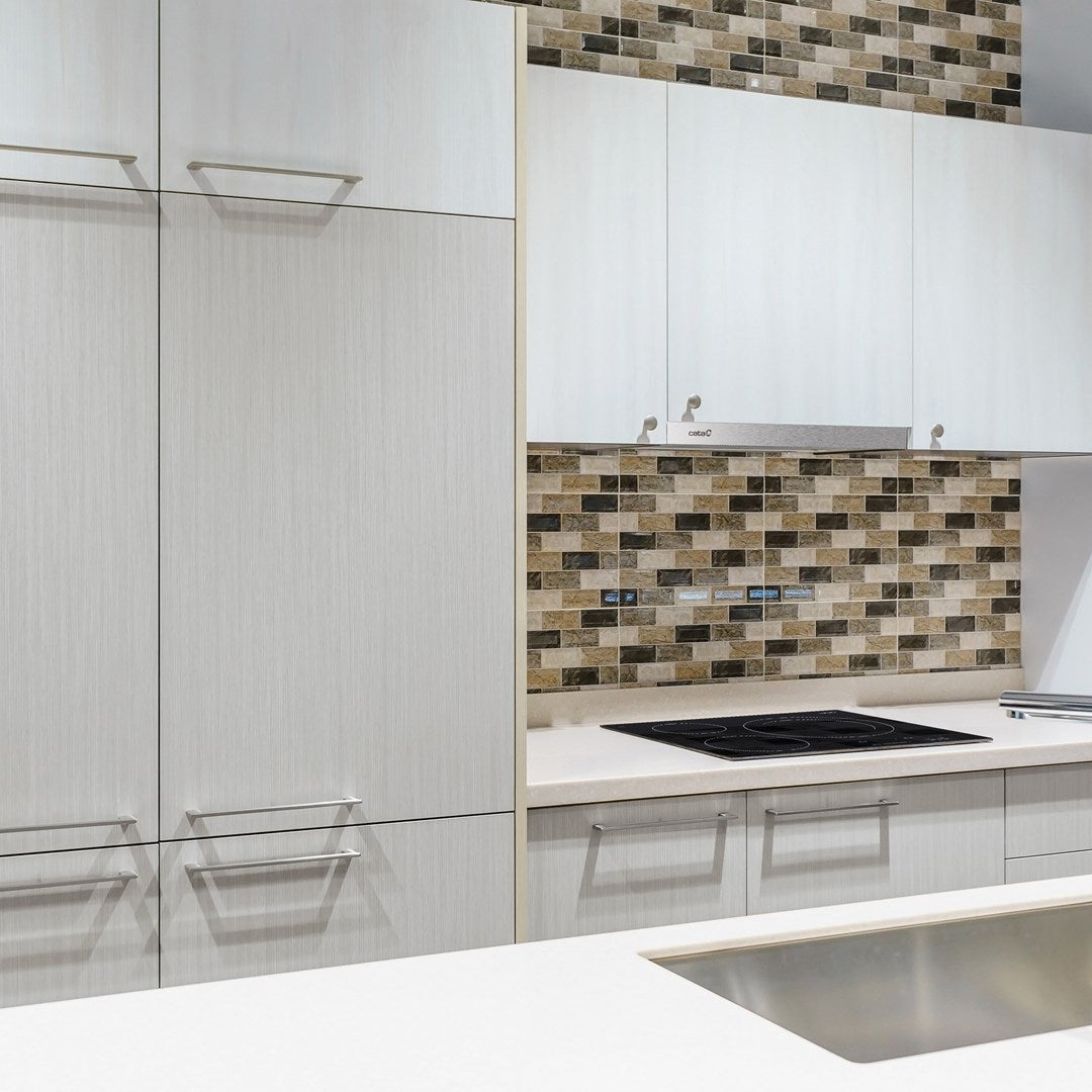 Cucina moderna con mobili bianchi, paraschizzi in piastrelle fantasia e piano cottura a induzione.