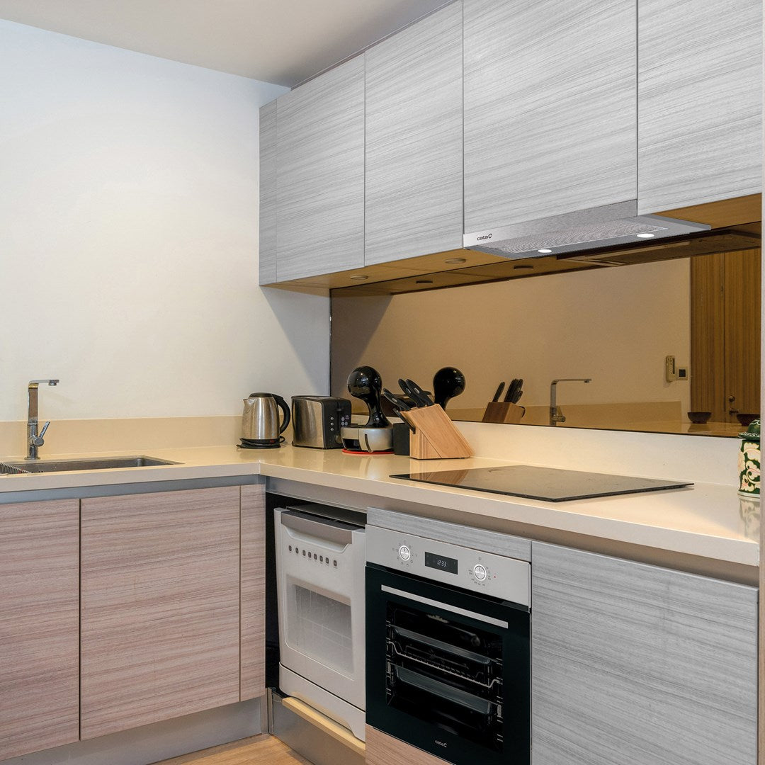 Moderna cucina con mobili in legno chiaro, elettrodomestici integrati, lavello, piano cottura e paraschizzi a specchio.