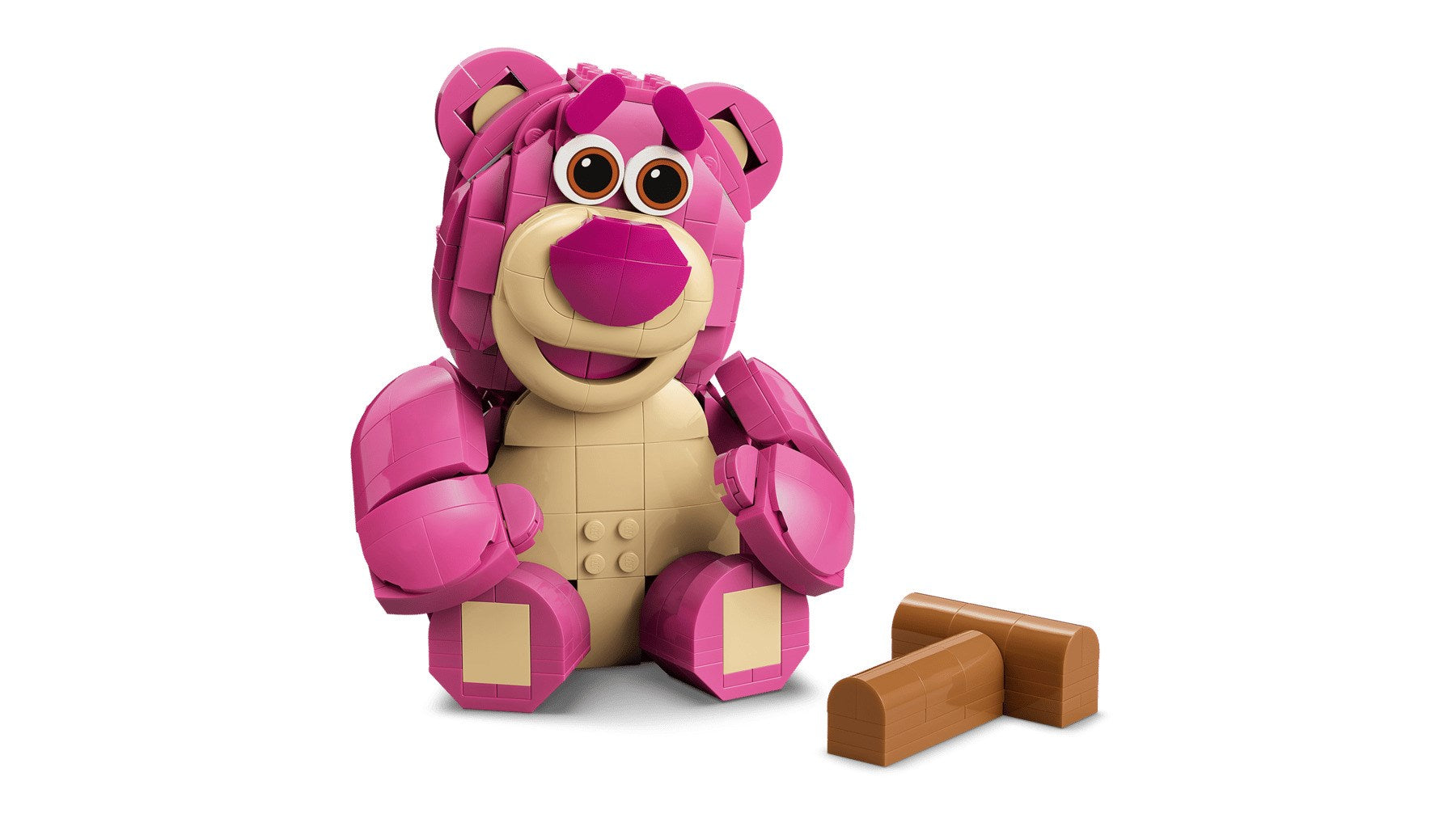 Różowy miś Lego z jaśniejszym brzuchem siedzi obok dwóch brązowych kloców.