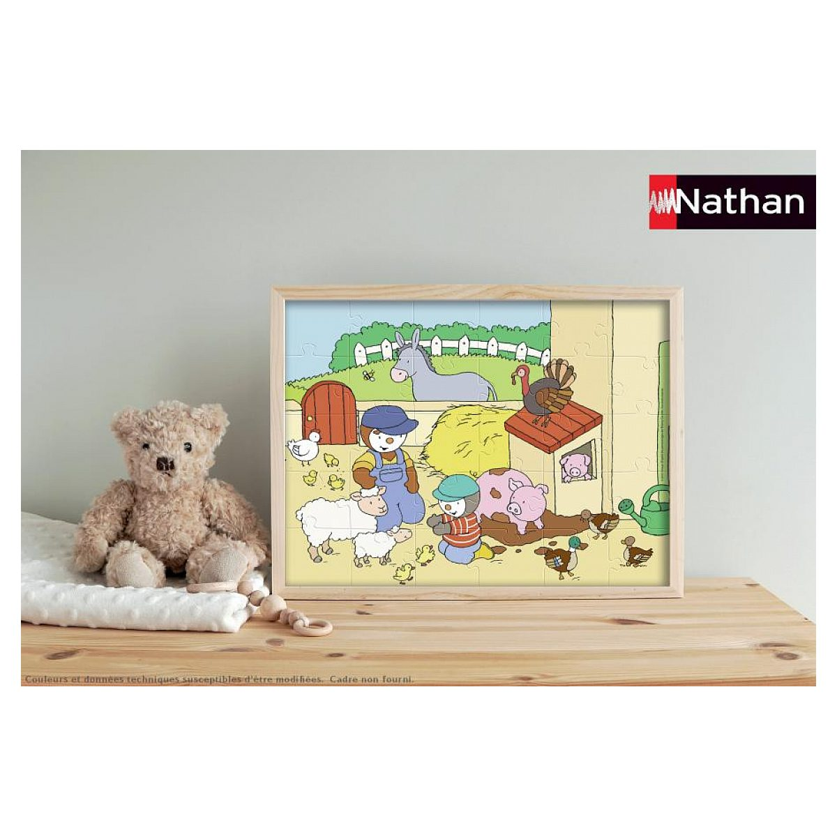 Ein gerahmtes Bauernhof-Puzzle mit Tieren und Figuren steht neben einem Teddybären auf einem Holztisch.