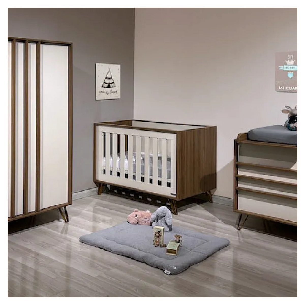 Babyzimmer mit Holzmöbeln, Kinderbett, Wickeltisch, Schrank und einer grauen Spielmatte mit Plüschtieren auf dem Boden.