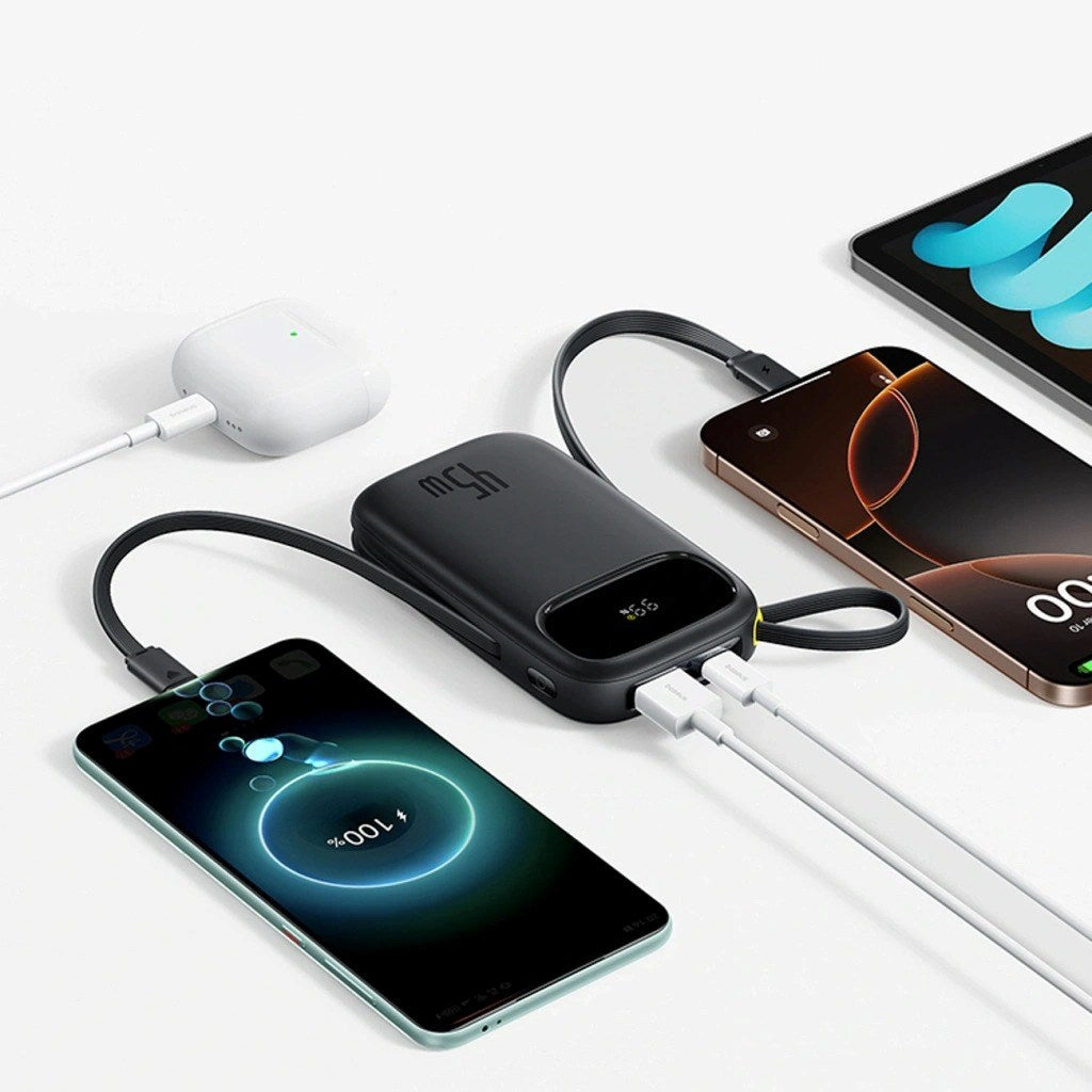Un power bank nero carica contemporaneamente uno smartphone, un tablet e gli auricolari.