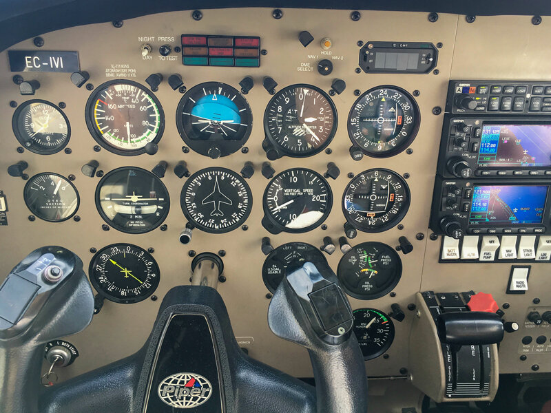 La cabina de un avión con numerosos instrumentos analógicos y dos mandos de control en primer plano.