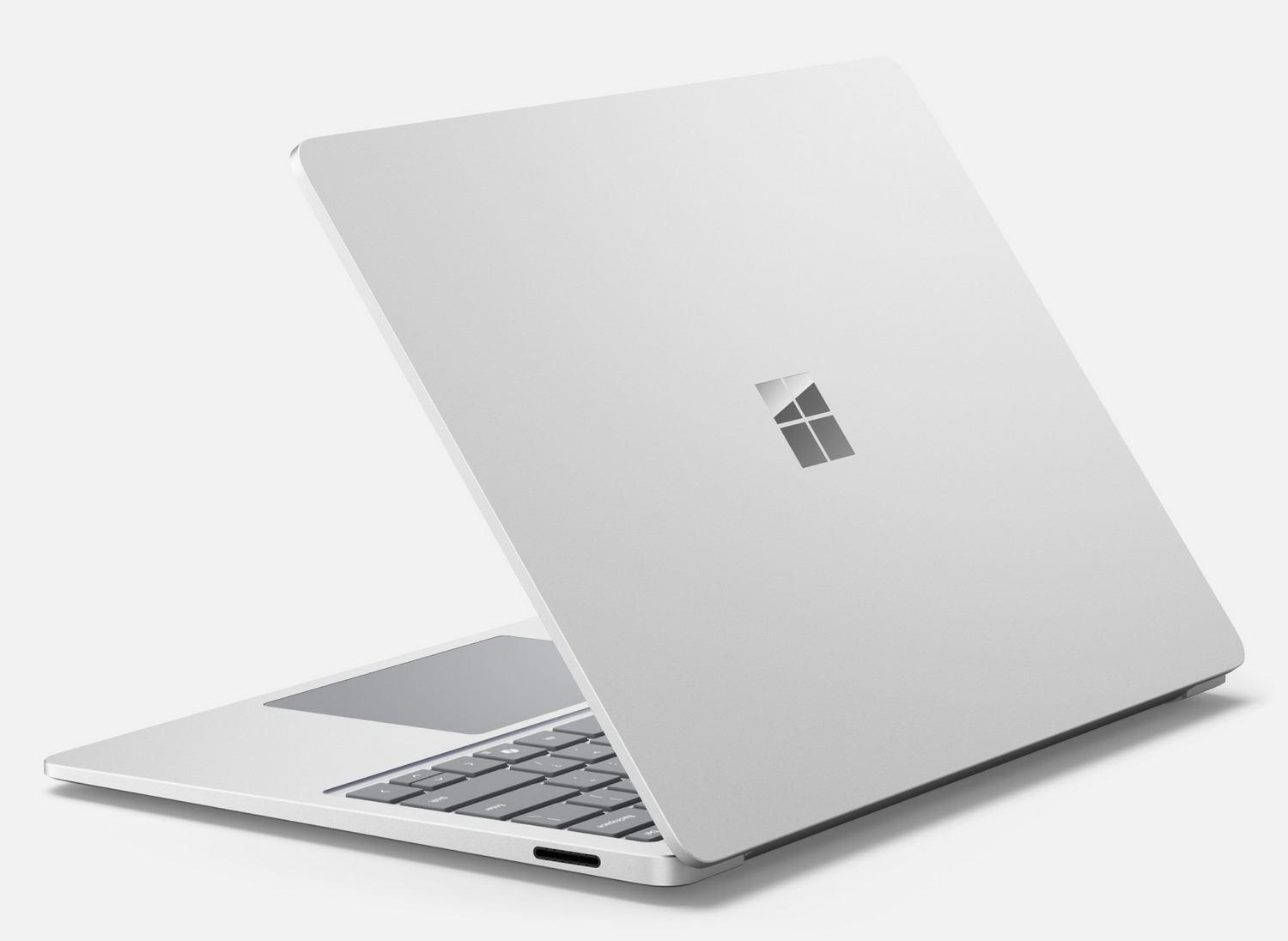 Un computer portatile argentato con un logo Windows sul coperchio chiuso si trova su una superficie chiara.