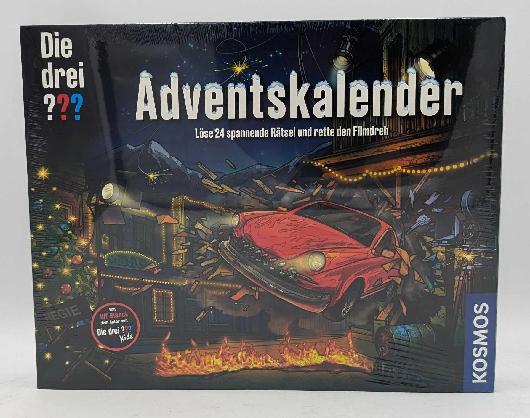 Ein Die-drei-Fragezeichen-Adventskalender mit rotem Auto, das durch eine Filmkulisse bricht, und Flammen am Boden.